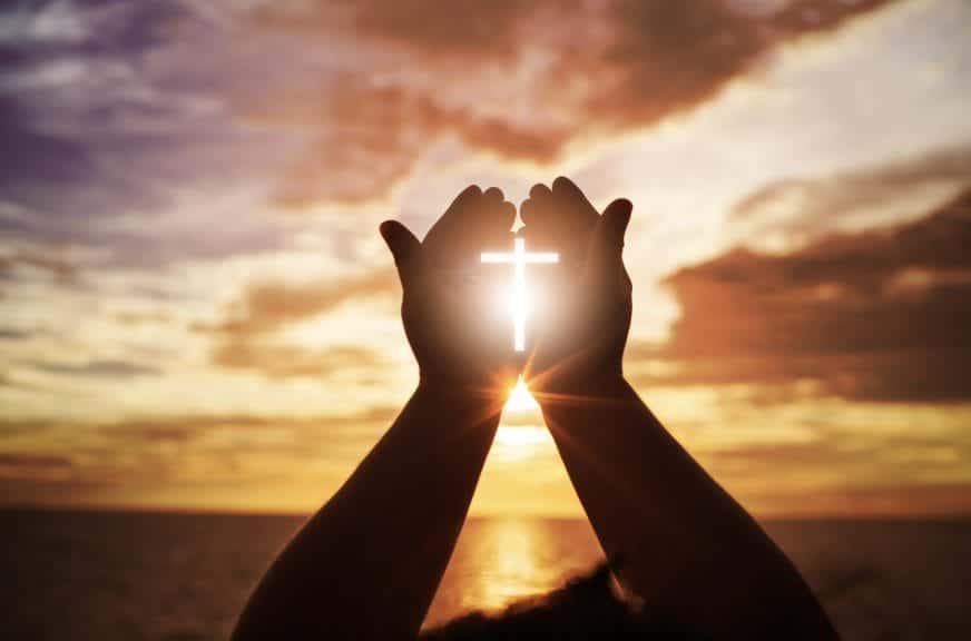 Prayer hands in front of Ocean.