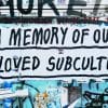 A graffitied wall with the text 'In memory of our beloved subculture'