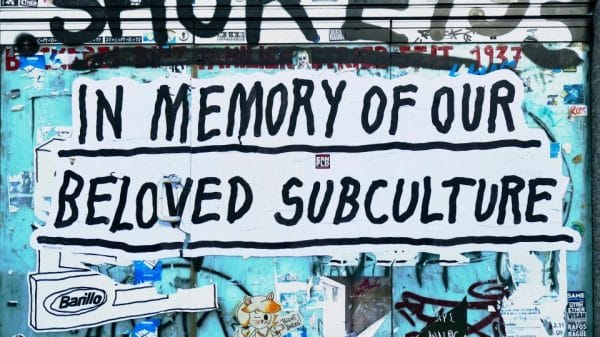 A graffitied wall with the text 'In memory of our beloved subculture'