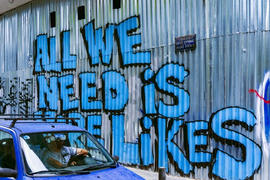 graffiti wall with the text 'all we need is more likes' referencing social media.