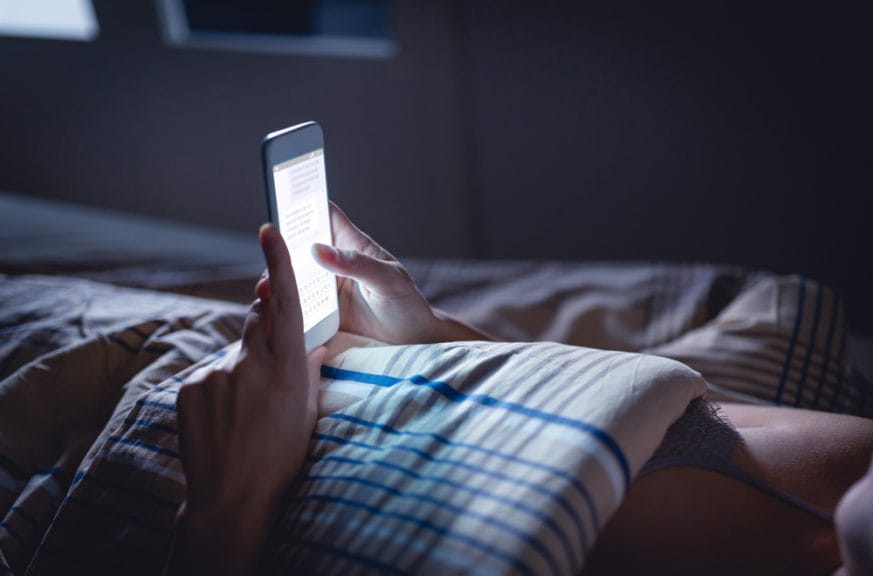 A person using a phone in bed. Screen time at night