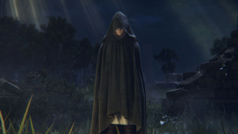 A hooded woman stands before a small golden bonfire.