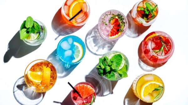 Summer cocktails drinks set. Assortment of multicolored strong and low alcoholic beverages for cocktail party. White background, hard light, shadows pattern, top view