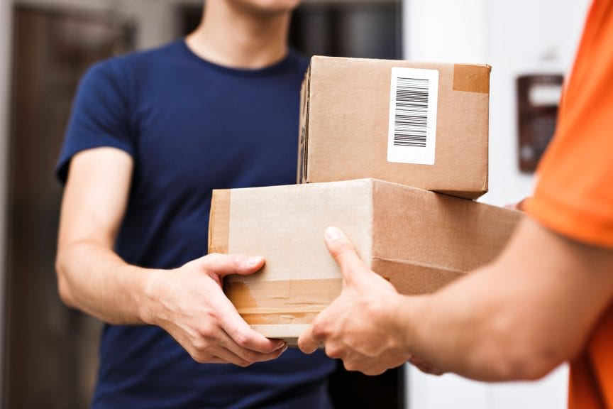 A person wearing an orange shirt is delivering parcels to a client.