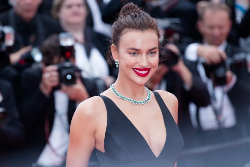 A tall brunette woman in a black low-cut gown and red lipstick with her hair in a bun