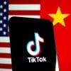 Phone with TikTok logo pictured in front of American and Chinese flags