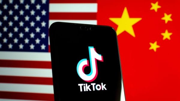 Phone with TikTok logo pictured in front of American and Chinese flags