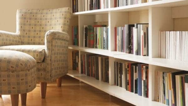 A armchair and ottoman sitting in front of a bookshelf.