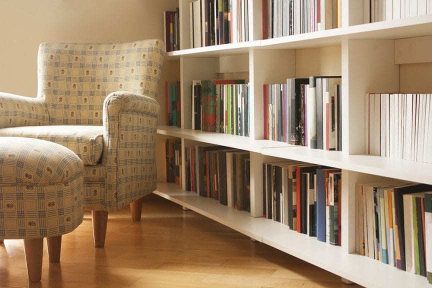 A armchair and ottoman sitting in front of a bookshelf.