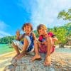 Kids sitting on tree in front of the ocean