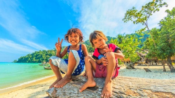 Kids sitting on tree in front of the ocean