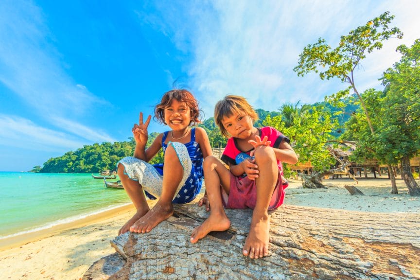 Kids sitting on tree in front of the ocean