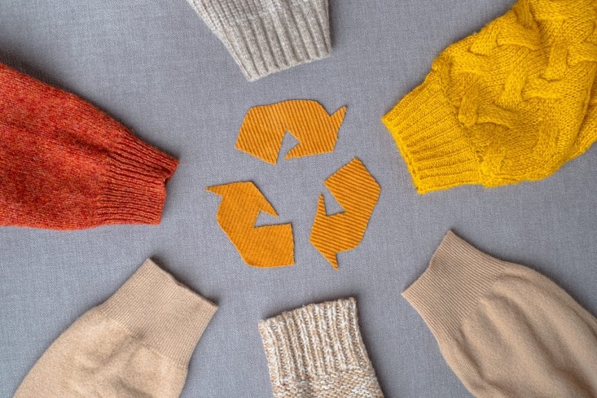 Recycling emblem, surrounded by the sleeves of clothing