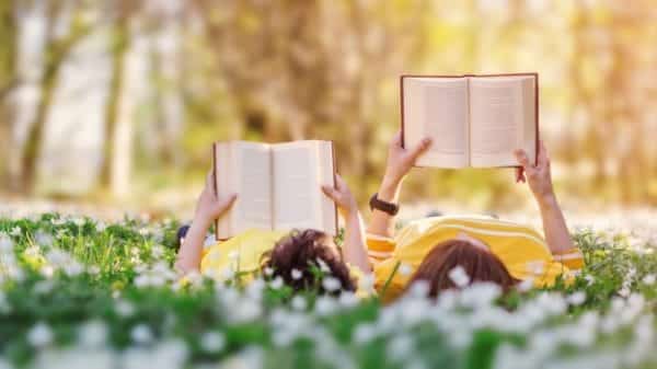 two people lying in grass and reading