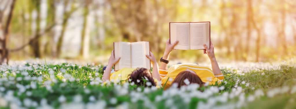 two people lying in grass and reading