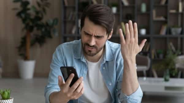 Image shows a person frustrated with their phone.