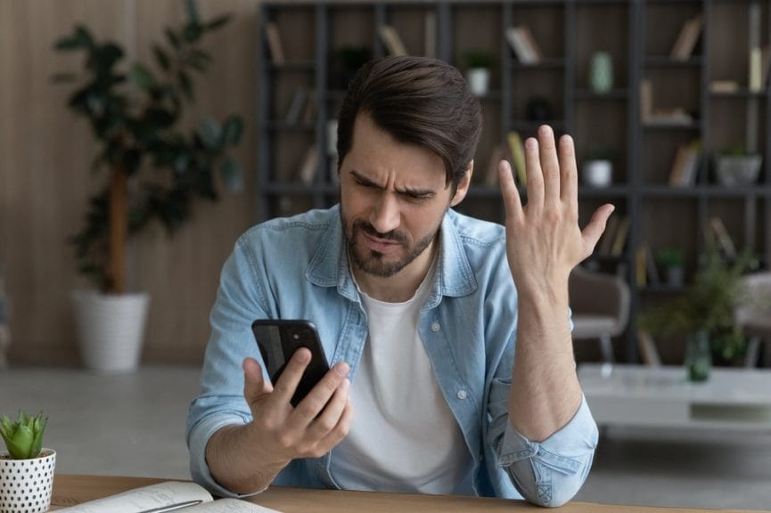 Image shows a person frustrated with their phone.