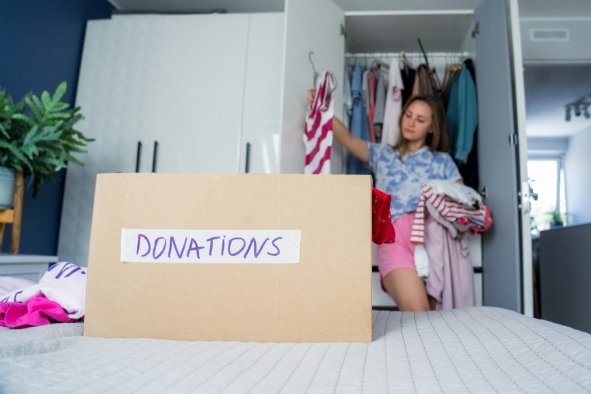 Woman putting clothes into a cardboard box labeled "donation" 