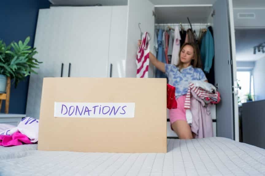 Woman putting clothes into a cardboard box labeled "donation"