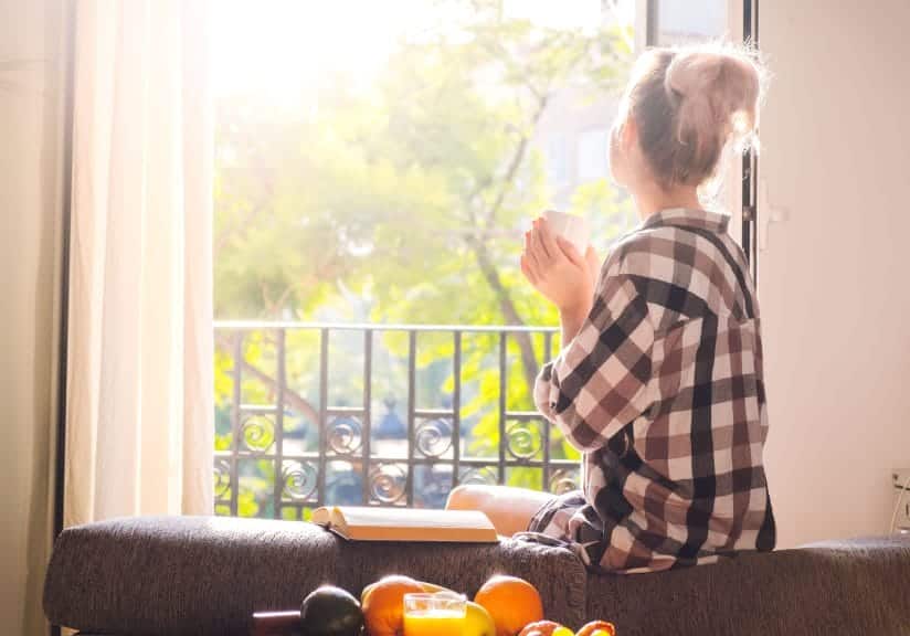 woman perched on the couch looking out at a balcony holding a mug. When studying abroad, it's important to take a breather as much as you'd like to see the sights.