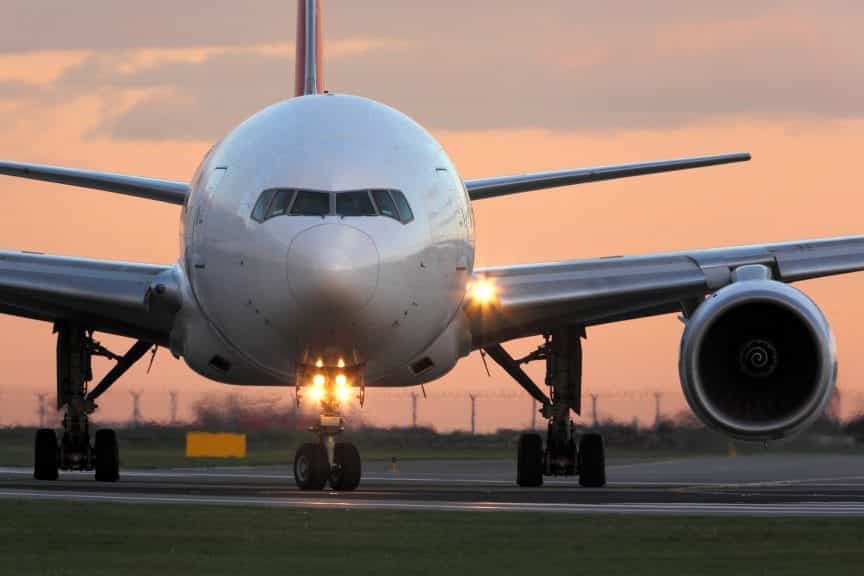Modern civil passenger airliner taking off at airport during sunset.