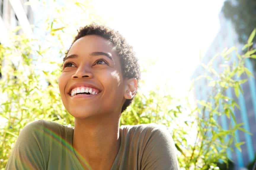 A woman smiling outside in nature on a sunny day