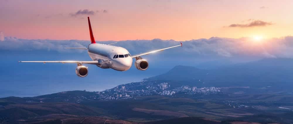 airplane flying during sunset with mountains in the background