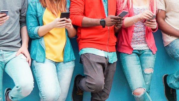 A group of teenagers against a wall on their phones watching videos and scrolling through social media