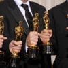 Five gold Oscar statues being held