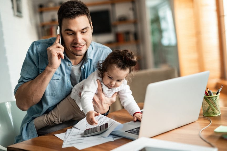 young dad with child in arms, working from home 