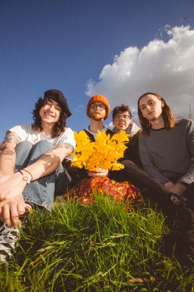 The band Bears in Trees, photographed with flowers against a bright blue sky. 