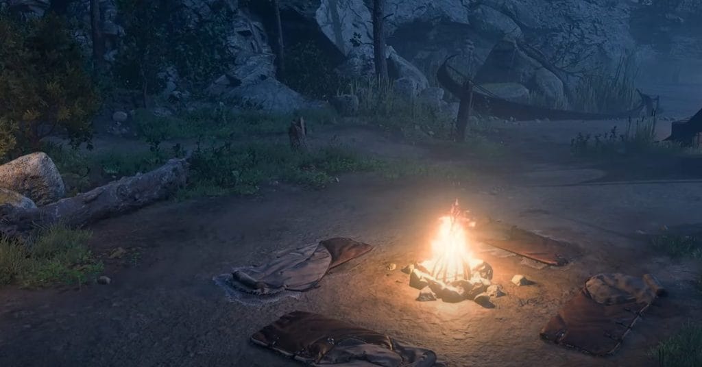 A bright campire surrounded by hide sleeping rolls on a beach at night.
