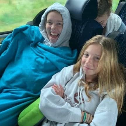 Two girls sitting on a bus during a long car trip.