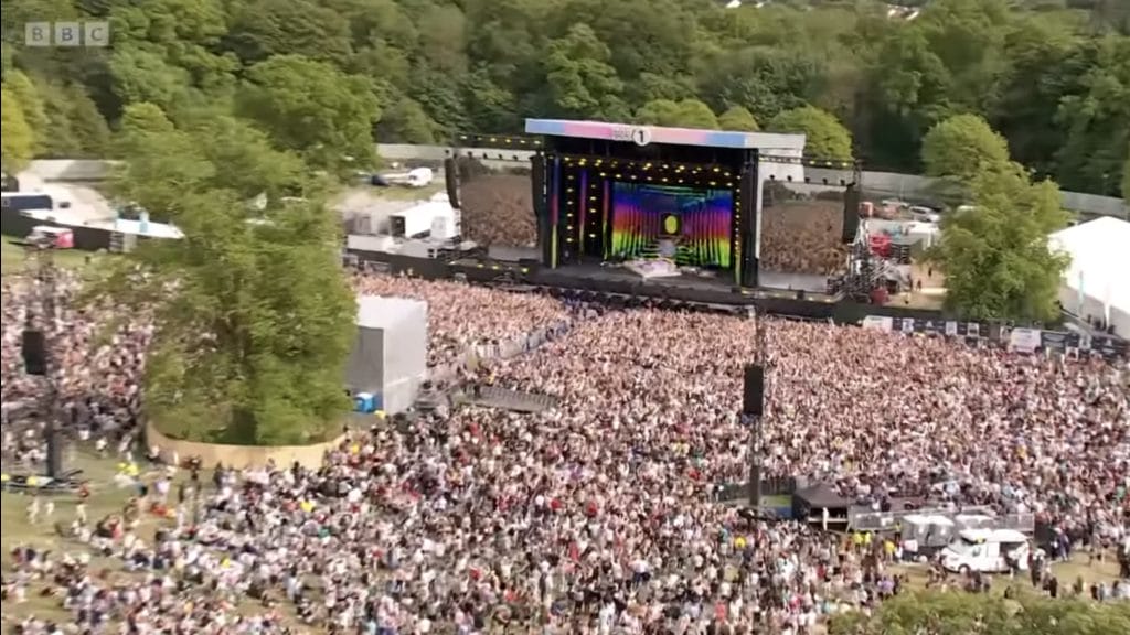 Singer on stage with crowds of people watching