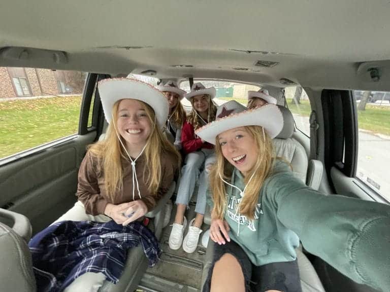 Group of girls in car wearing cowboy hats.