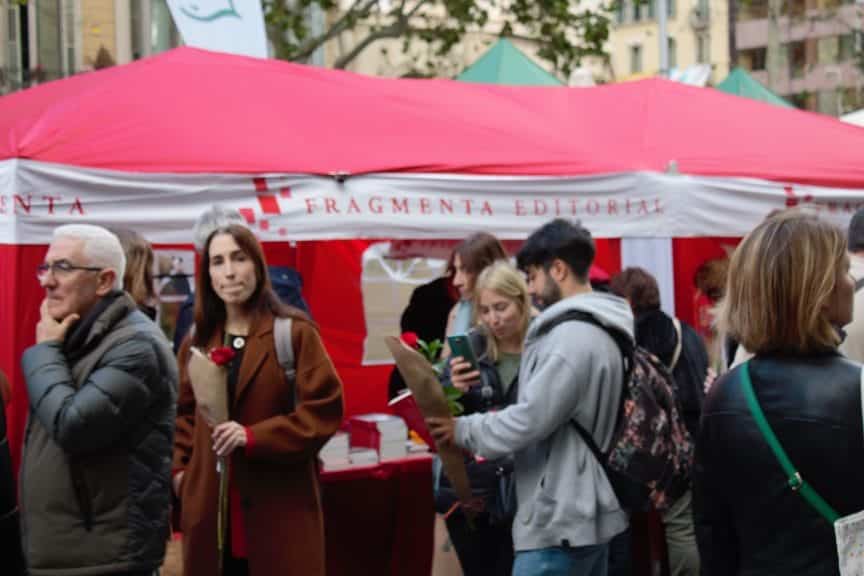 A couple admiring a rose in front of a stall selling books.