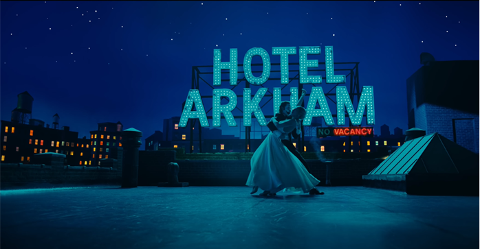 Image shows Fleck and Quinn dancing with Hotel Arkham sign as backdrop.