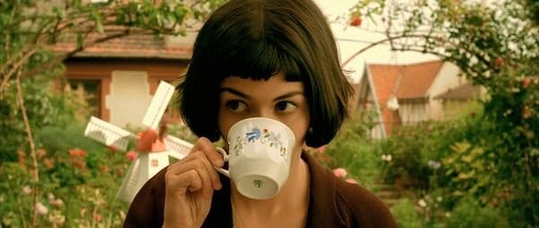 Amelie sits in a beautiful garden in springtime and drinks tea.