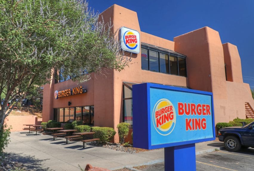 a pale red building with a blue square 'Burger King' sign in front of it