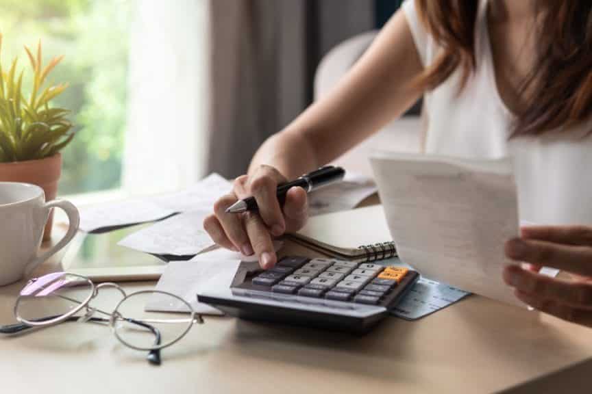 High school student sitting at a calculator while looking at payment forms.