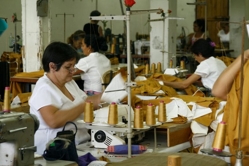 Women sewing behind machines in sweat factories as part of consumer culture.