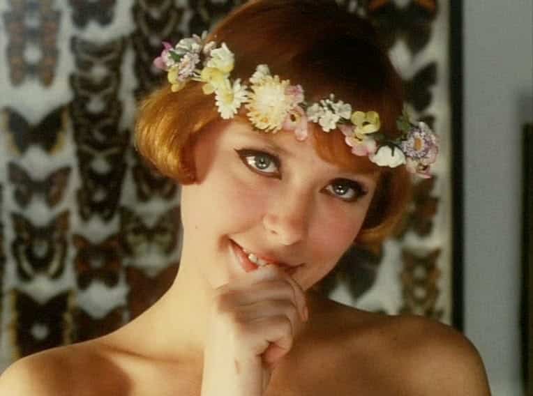 Marie #2 stares dreamily into the camera, wearing a flower crown, with a springtime background of butterflies.