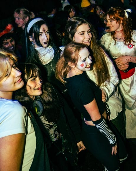 A person dressed in a scary nun outfit stands in the crowd of a punk show