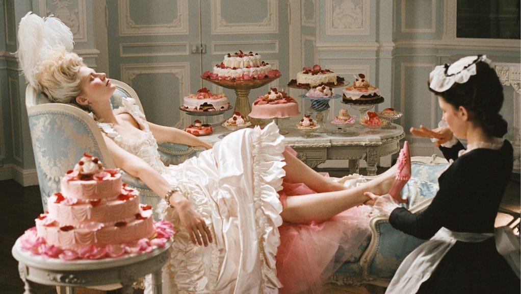 Marie Antoinette relaxes, surrounded by dreamy  pastel desserts.