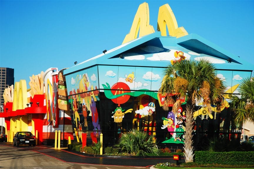 A building in the shape of a Happy Meal box. It has yellow arches at the top and is painted with blue sky, clouds, and McDonald's characters