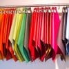 A rainbow of coloured fabric swatches hang on a clothing hanger.