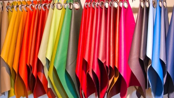 A rainbow of coloured fabric swatches hang on a clothing hanger.