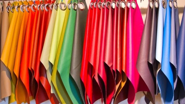 A rainbow of coloured fabric swatches hang on a clothing hanger.