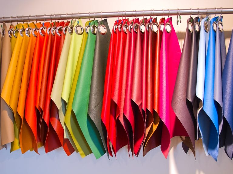 A rainbow of coloured fabric swatches hang on a clothing hanger.