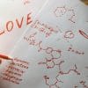 The concept of love as hormones. Sheets of paper written with formulas in search of an answer to the question of what is love .